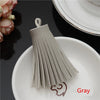 A gray leather tassel fringe craft supplies set displayed on a white plate.