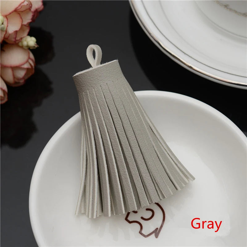 A gray leather tassel fringe craft supplies set displayed on a white plate.