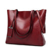 A deep red waxed leather bucket bag featuring dual straps and a smooth finish.