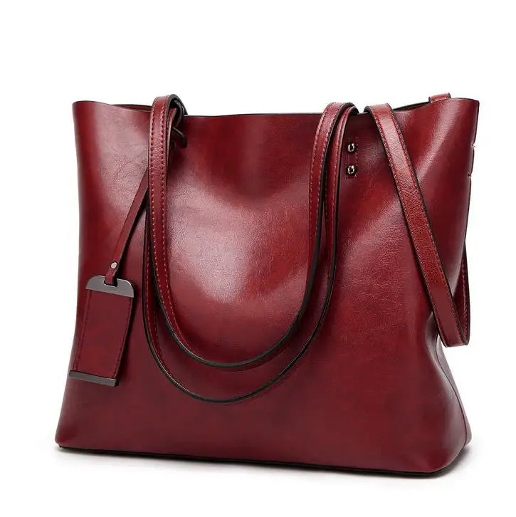 A deep red waxed leather bucket bag featuring dual straps and a smooth finish.