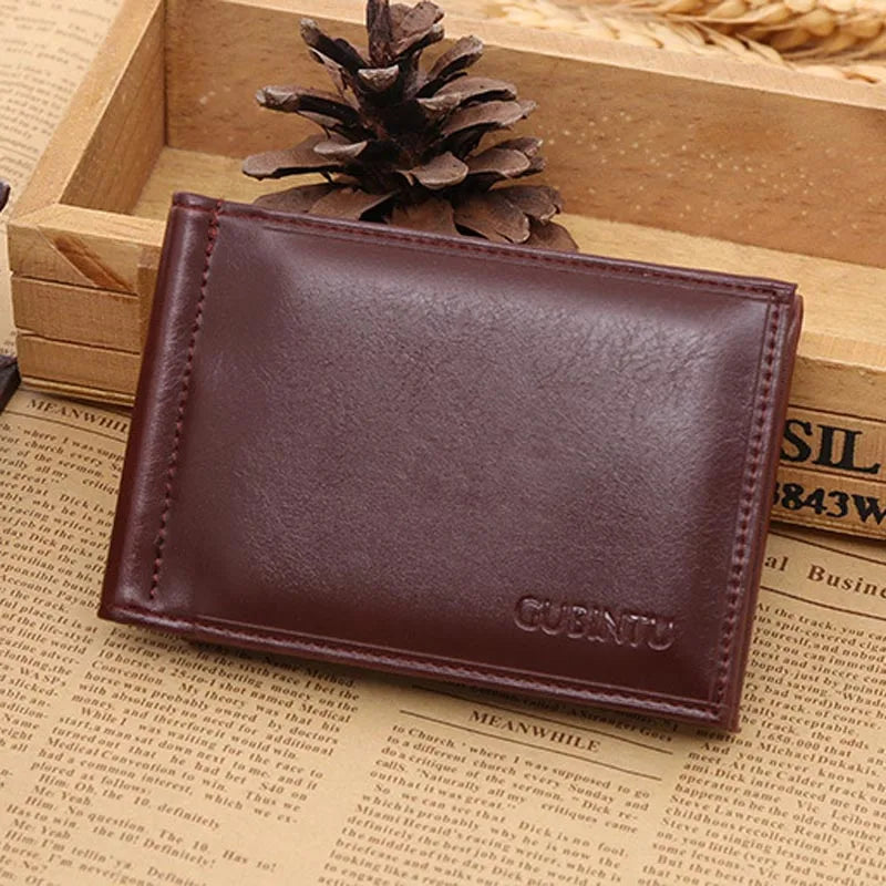 A brown leather money clip wallet resting in a wooden box next to a pinecone.