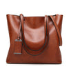 A brown waxed leather bucket bag with dual straps shown from the front.