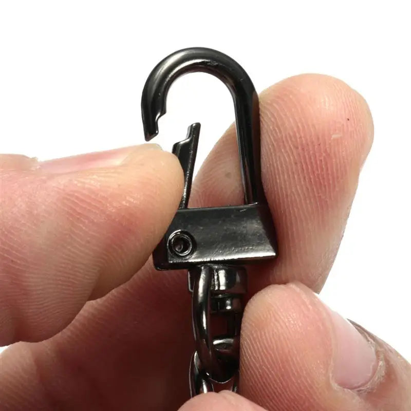 A hand holds a black metal bag chain strap with clips, showing the clasp mechanism.