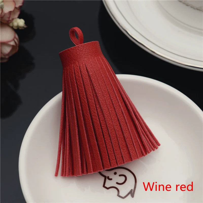 A set of red leather tassel fringe craft supplies displayed on a white plate.