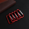 A set of five red aluminum carabiner key rings resting on a dark textured surface.