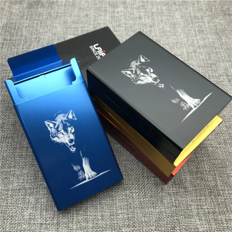 A blue custom engraved cigarette case is shown next to a black and gold box with a wolf design.
