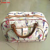 A large white and multi-colored patterned PU leather travel duffel bag with brown leather handles.
