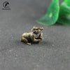 A vintage brass rat figurine is shown resting on a dark surface.
