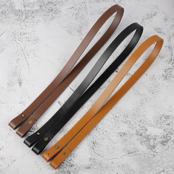 Three adjustable PU leather crossbody straps in brown, black, and tan laid diagonally on a white surface.
