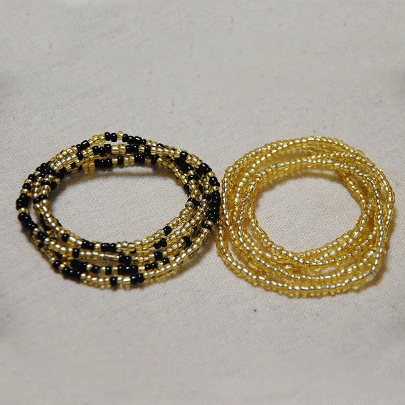 Two strands of colorful belly bead chains, one black and gold, and one solid gold color.