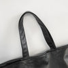 A black oversized PU leather tote bag shown from the top, featuring a handle.