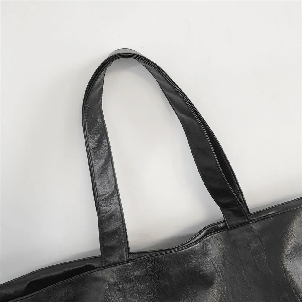 A black oversized PU leather tote bag shown from the top, featuring a handle.