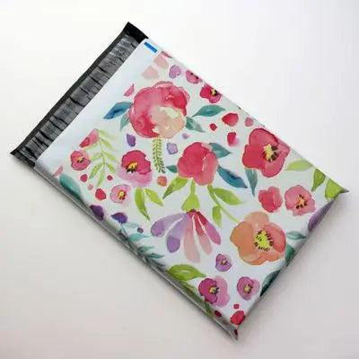 Une pile de pochettes d'envoi auto-scellantes à motif floral rose et vert.
