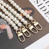 A string of white pearls with gold clasps is displayed on a dark background.
