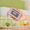 Una mano sostiene una cartera con soporte para tarjeta de crédito de RFID, rosa, con una cadena dorada.