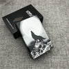 A black and white photograph of a custom engraved cigarette case featuring a silhouette of a wolf against a bright moon and s