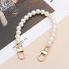 A delicate strand of white pearls on a gold-toned strap, suitable for handbags and purses.