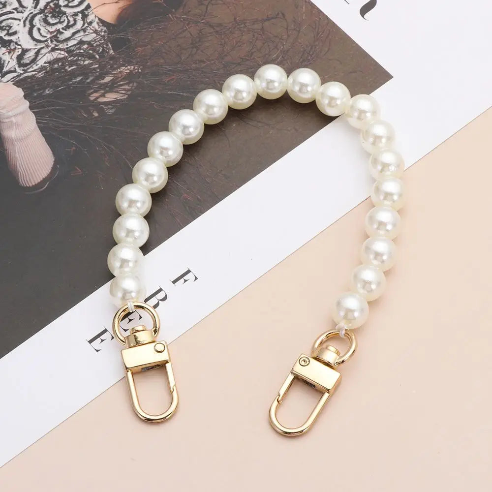 A delicate strand of white pearls on a gold-toned strap, suitable for handbags and purses.