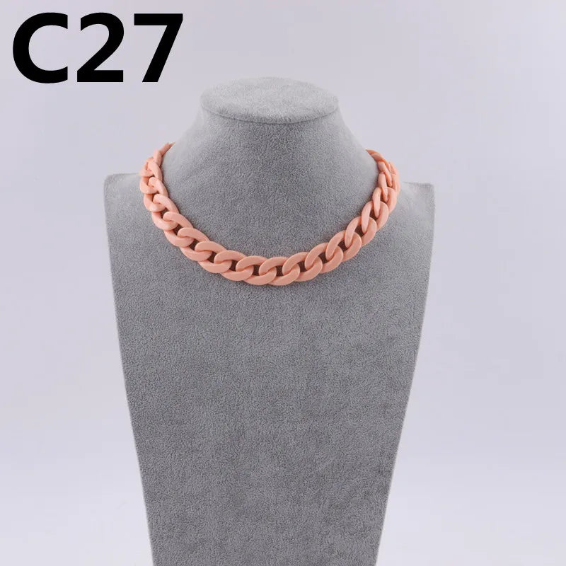 A close-up of a pink acrylic link chain necklace displayed on a gray mannequin neck.