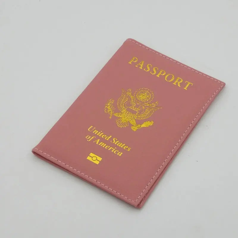 A pink leather passport holder with gold lettering and an eagle design.