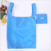 A bright blue eco-friendly foldable shopping bag next to a folded blue bag and a citrus fruit.