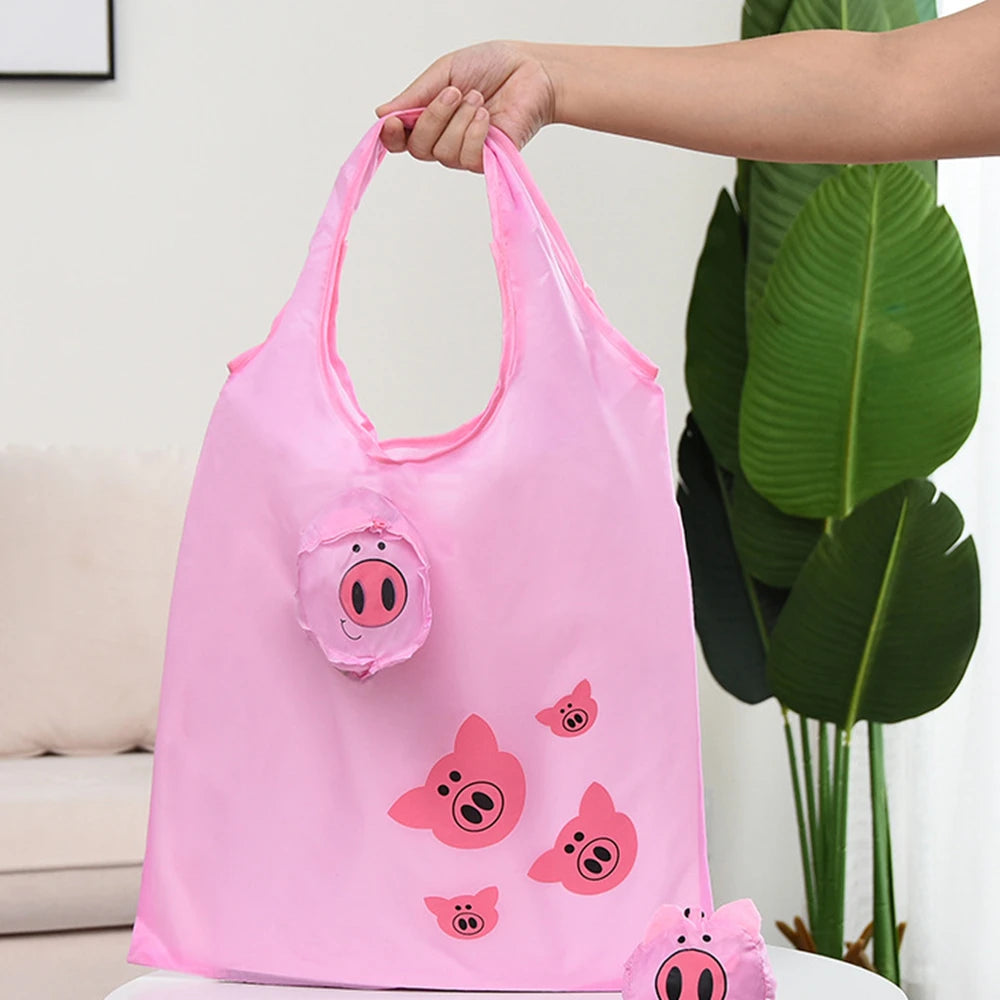 Une main tient un sac de shopping cartonné rose et pliable, écologique, avec un design de porc.