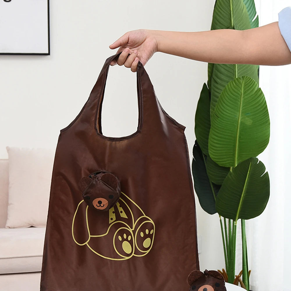 Un sac de shopping en cuir marron avec un dessin de ours de dessin animé encadré en or, tenu par une main.