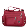 A maroon waterproof nylon crossbody tote bag for women with multiple compartments.