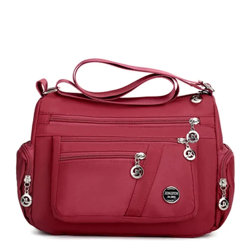 A maroon waterproof nylon crossbody tote bag for women with multiple compartments.