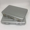 A silver aluminum credit card and ID holder case with a hinged lid resting on a flat base.