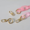 A collection of pink and gold adjustable detachable chain shoulder bag hardware including rings and clasps.