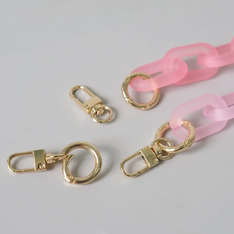 A collection of pink and gold adjustable detachable chain shoulder bag hardware including rings and clasps.