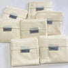 Several light beige eco-friendly foldable shopping bags are stacked and laid out.