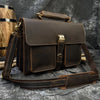 A dark brown vintage Crazy Horse leather briefcase with a leather strap is shown against a dark background.