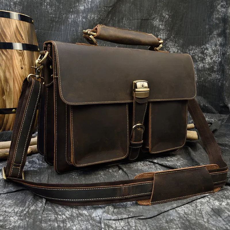 A dark brown vintage Crazy Horse leather briefcase with a leather strap is shown against a dark background.