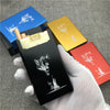 A hand holds a black cigarette case featuring an engraved wolf design, alongside two gold and red boxes.