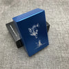 A blue custom engraved cigarette case with a silhouette of a wolf on the lid, resting on a dark box.