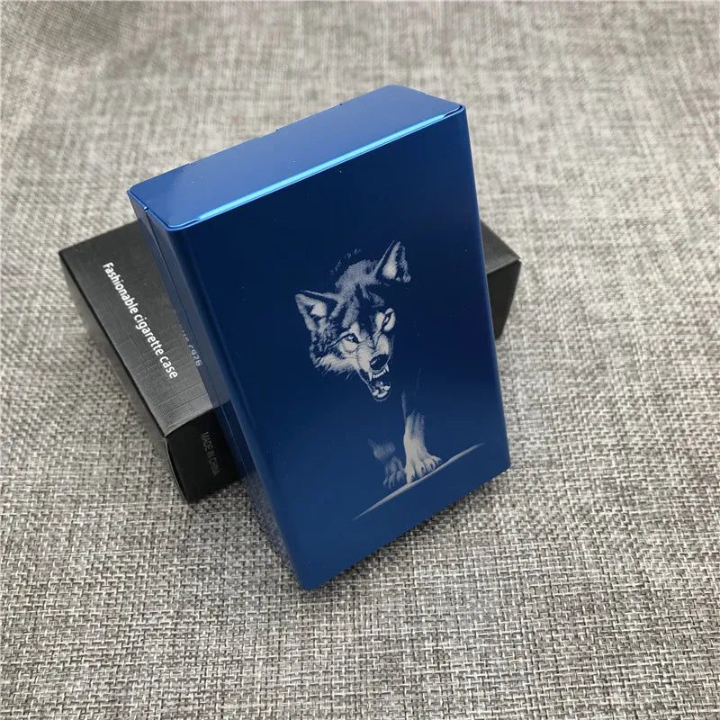 A blue custom engraved cigarette case with a silhouette of a wolf on the lid, resting on a dark box.