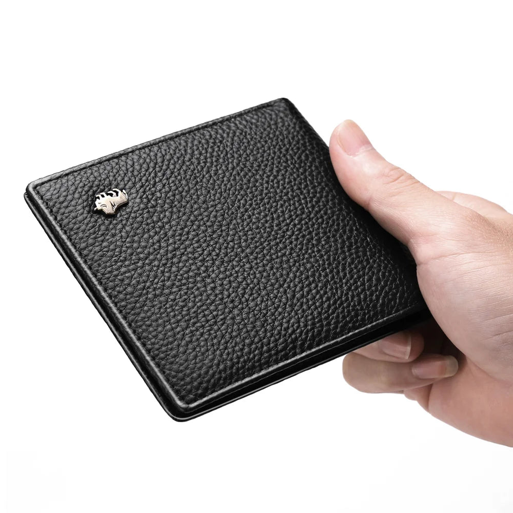 A black genuine leather bifold wallet with a silver-colored coin or card holder is held in a hand.
