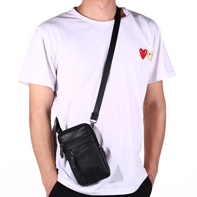 A person wearing a white t-shirt is holding a black genuine leather crossbody phone pouch belt bag.