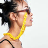 A woman wearing a gold chunky chain strap on her nose and a black top.