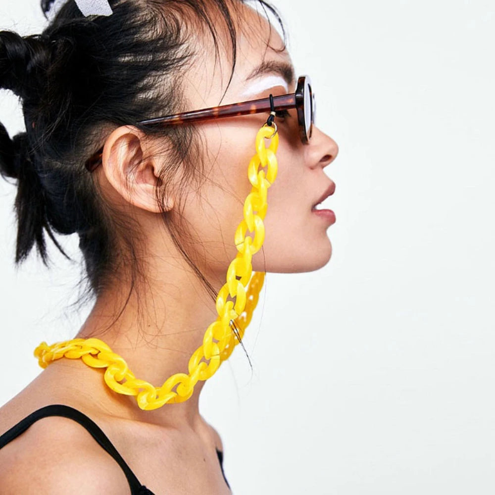 A woman wearing a gold chunky chain strap on her nose and a black top.