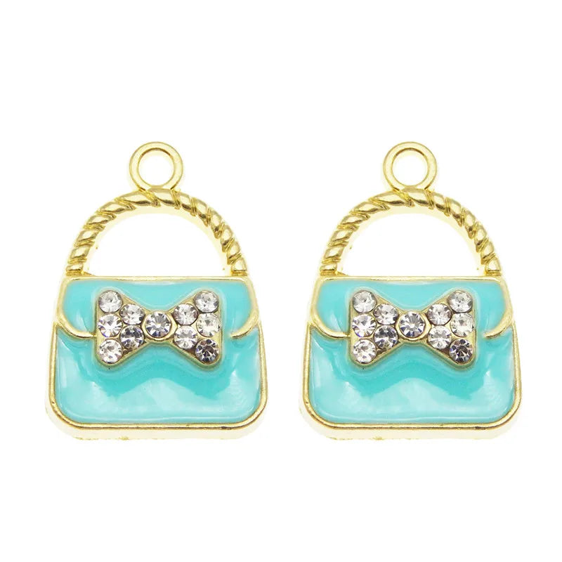 Une paire de charmons de sac ton or avec des nœuds en émail bleu clair et des perles scintillantes.