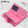 A pink leather card holder wallet with vertical stitching and a dark label is displayed on a white surface.