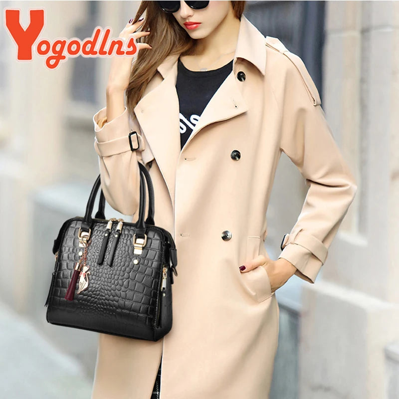 A woman models a beige trench coat and a black crocodile-embossed leather tassel shoulder bag.