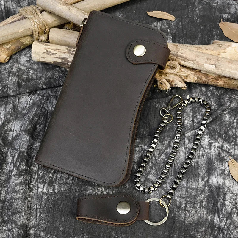 A dark brown genuine leather bifold wallet with a metal chain is displayed on a dark gray textured surface.