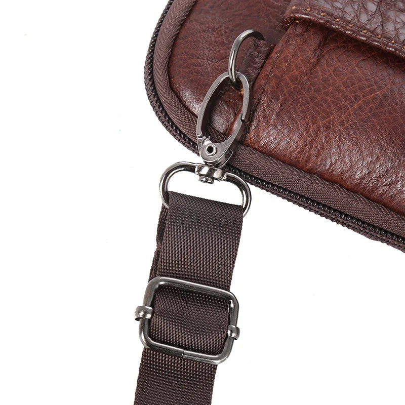 A brown genuine leather crossbody phone pouch with a silver metal clip and adjustable strap.