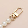 A gold-toned pearl strap with a clasp is shown against a light background.