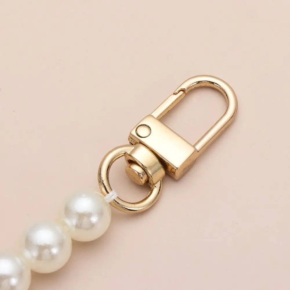 A gold-toned pearl strap with a clasp is shown against a light background.
