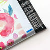 Vue rapprochée de pochettes d'envoi à motif floral scellées, avec une bande de code-barres noire sur le côté.